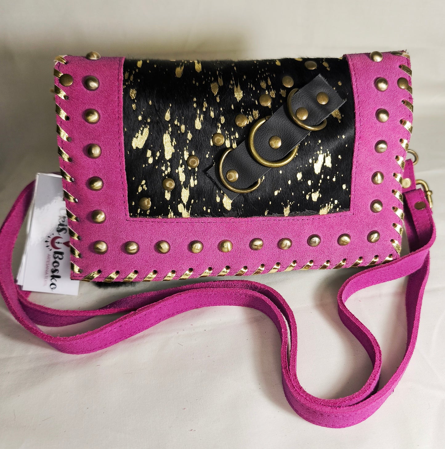 Bolso artesanal en piel con salpicaduras doradas y marco fucsia