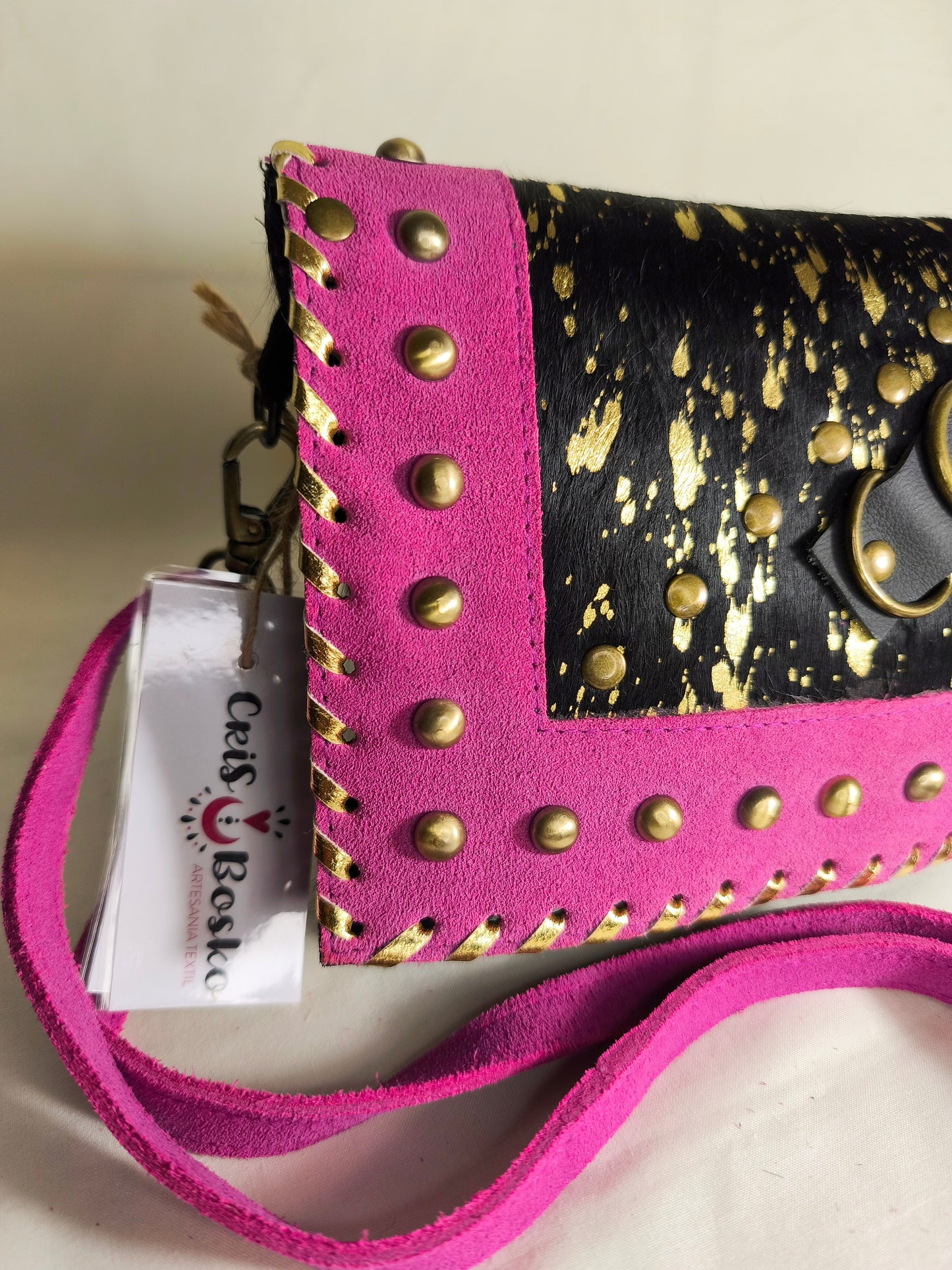 Bolso artesanal en piel con salpicaduras doradas y marco fucsia