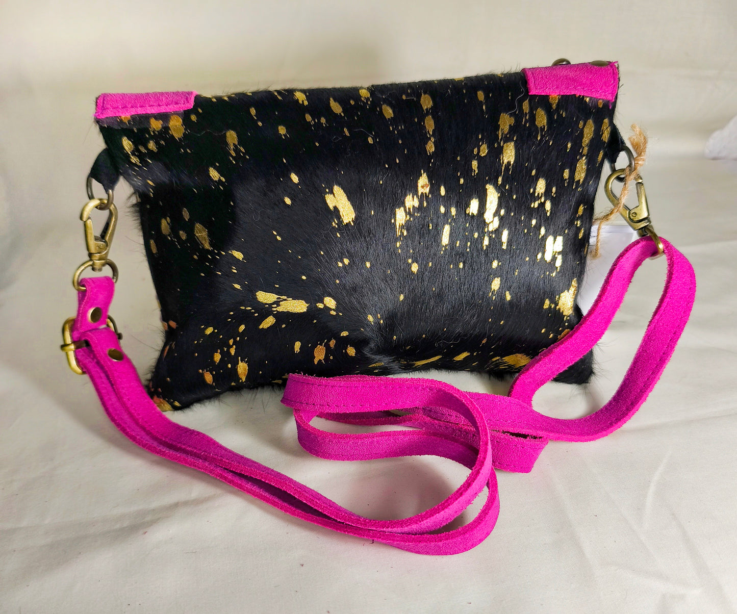 Bolso artesanal en piel con salpicaduras doradas y marco fucsia