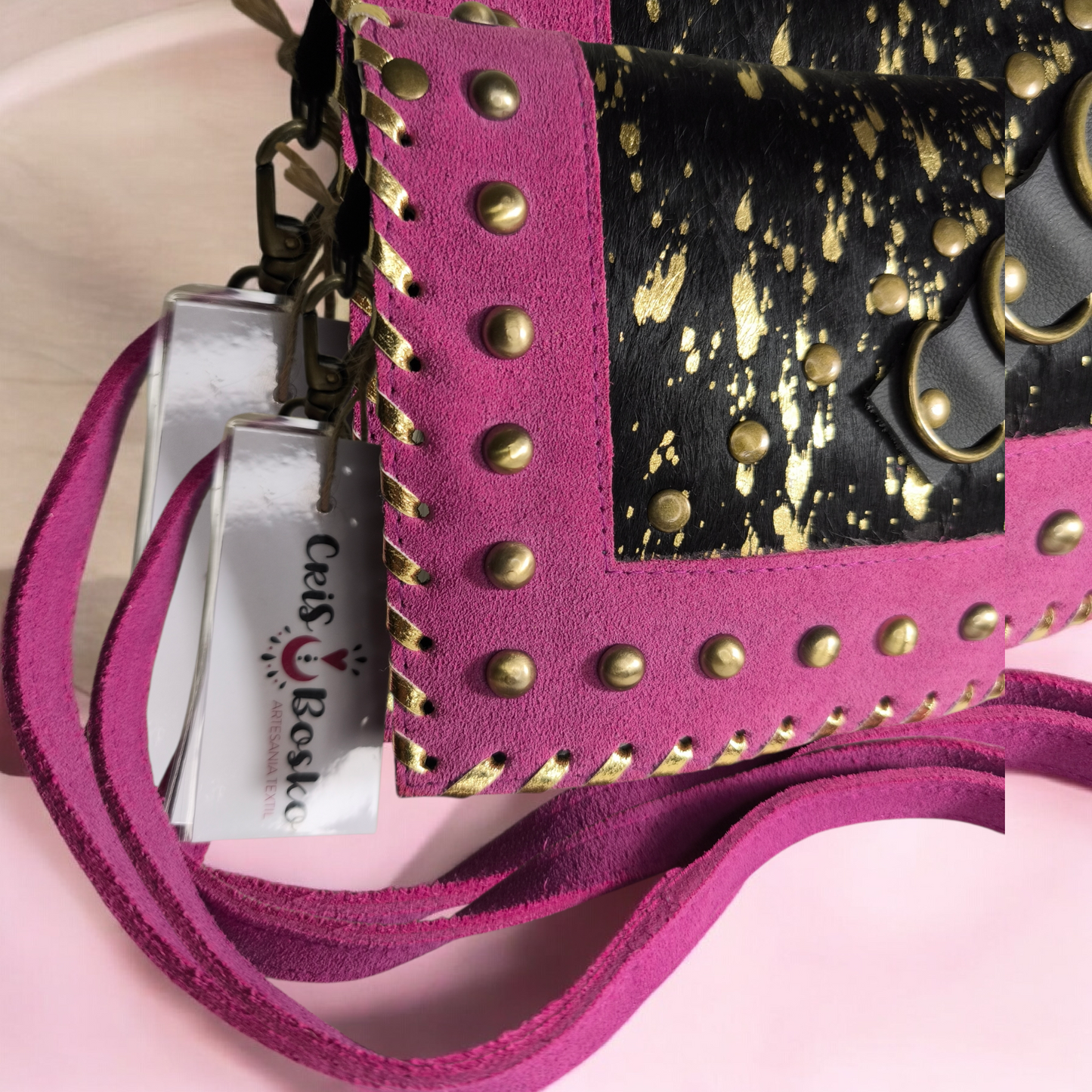 Bolso artesanal en piel con salpicaduras doradas y marco fucsia