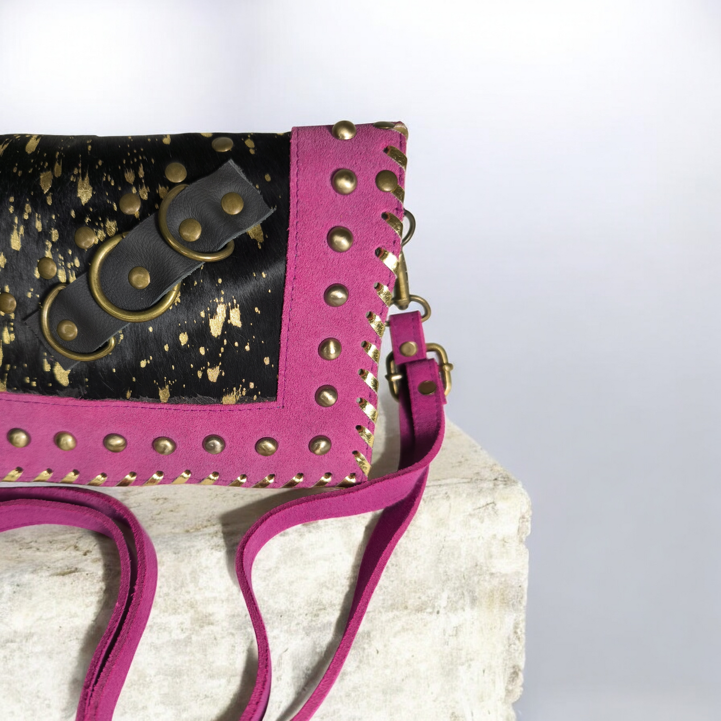 Bolso artesanal en piel con salpicaduras doradas y marco fucsia