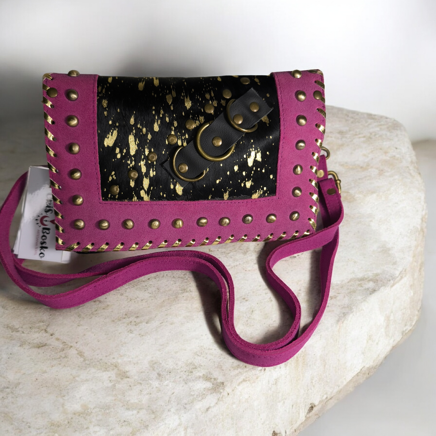 Bolso artesanal en piel con salpicaduras doradas y marco fucsia